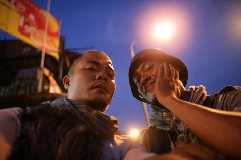 two men are looking down at soing in the dark