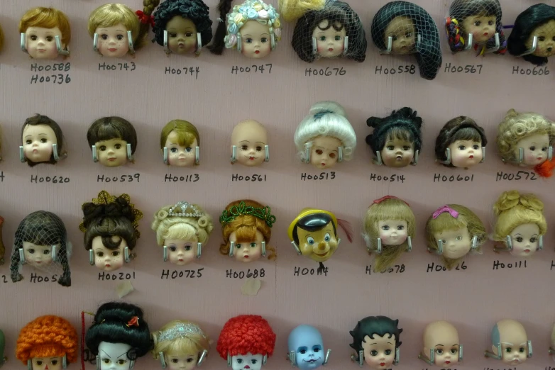 several heads and hairs in various wigs displayed on wall