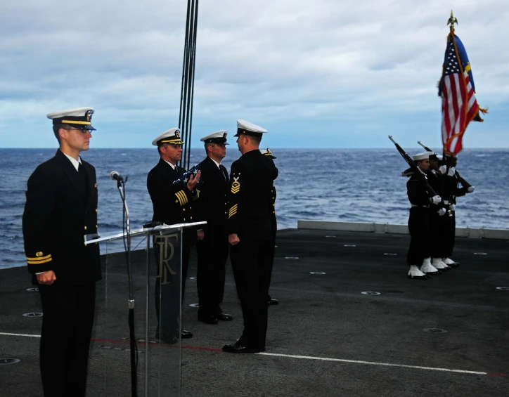 navy officials standing in front of the united states flag