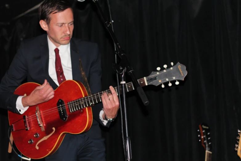 a man is playing his red guitar on the stage