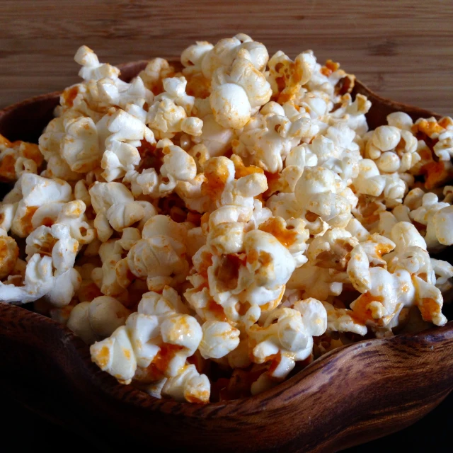 a wooden bowl filled with popcorn and topped with marsh