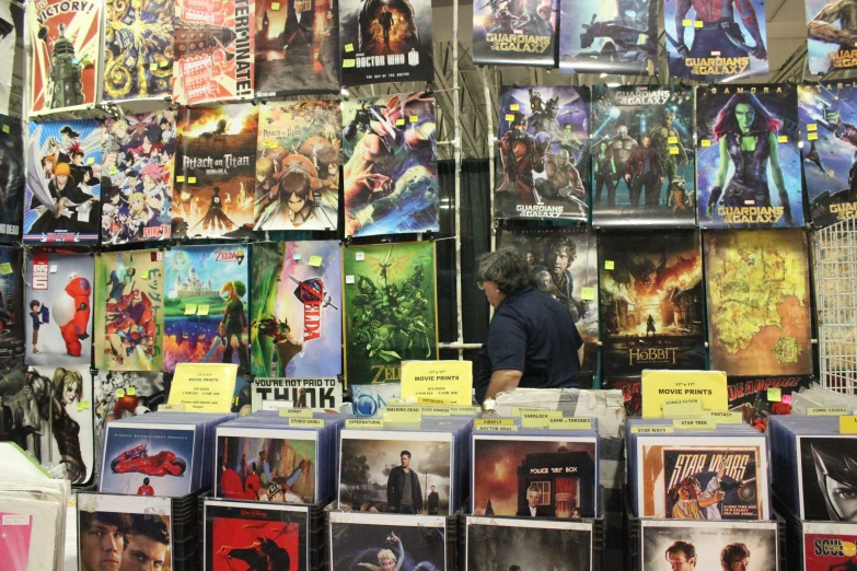 a man is buying posters for comics at an indoor fair