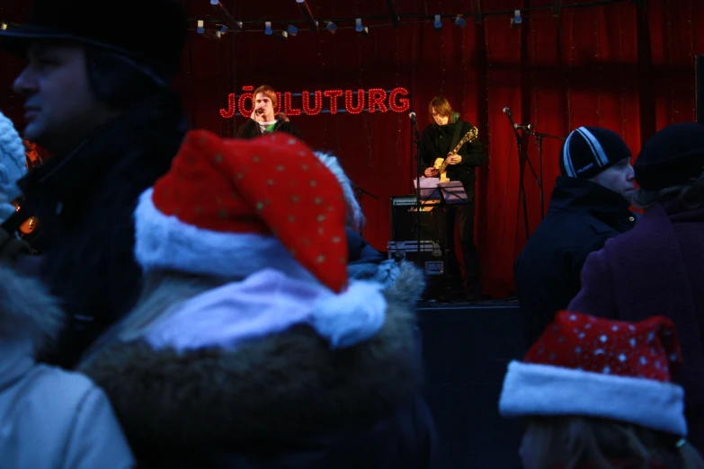 a group of people that are standing around wearing santa hats