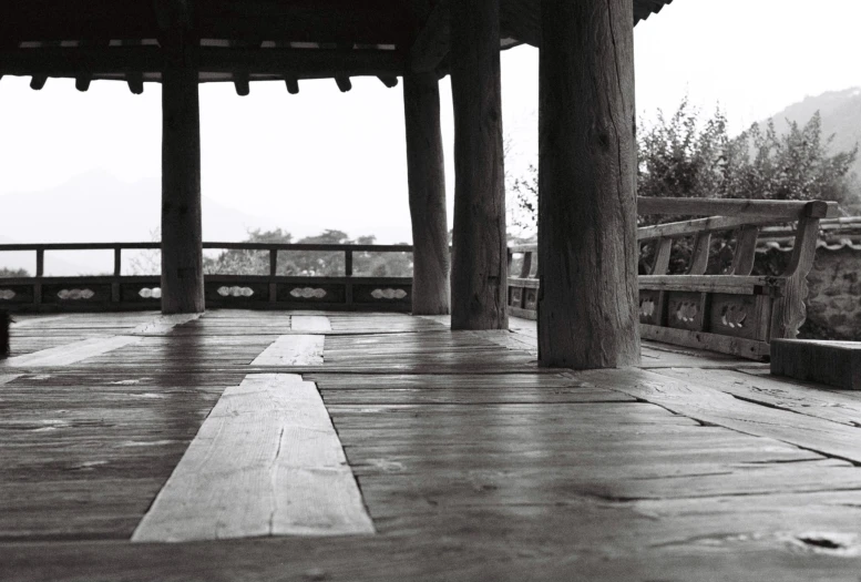 there is an empty wooden walkway in front of some columns