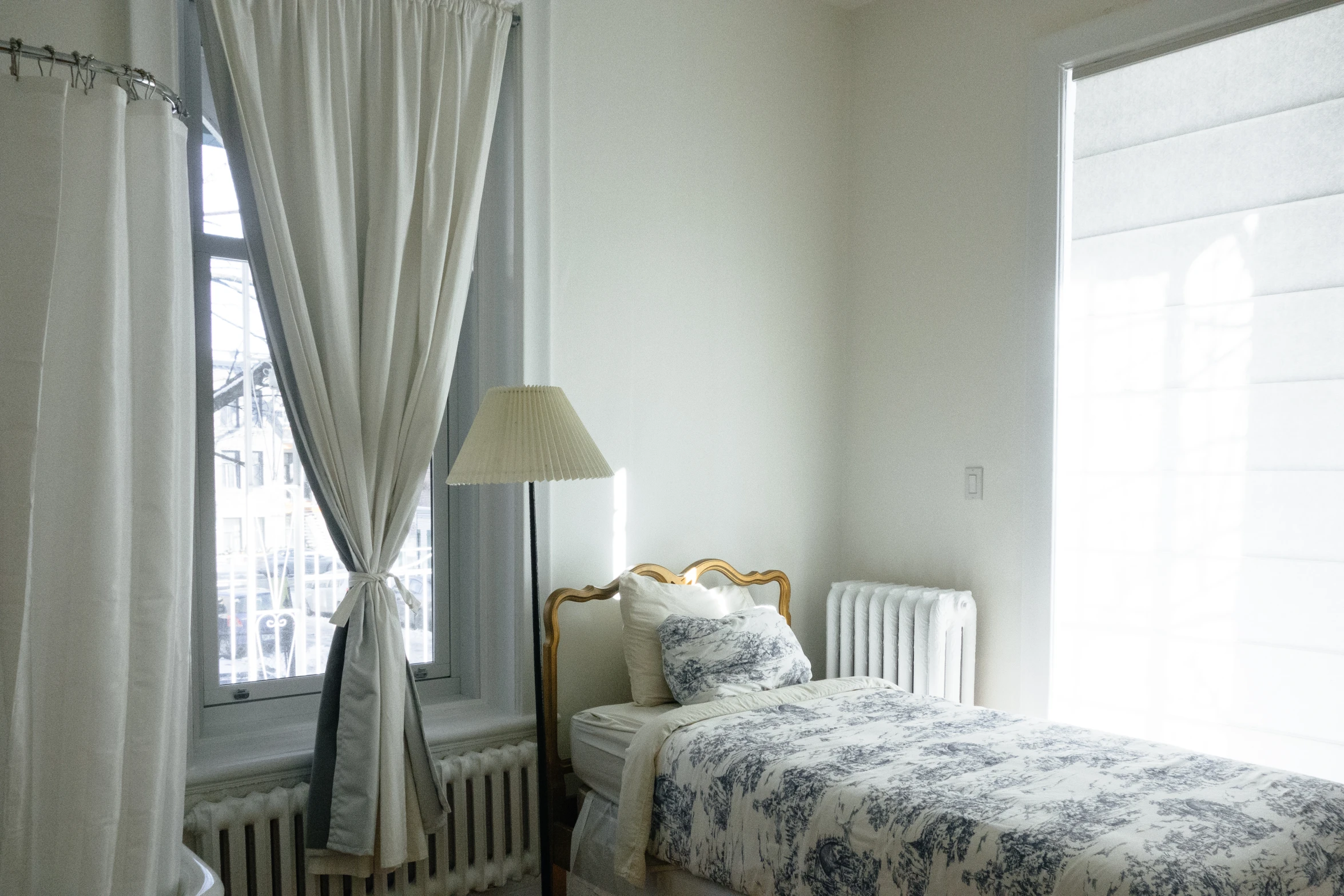 a large bedroom has two white beds with curtains