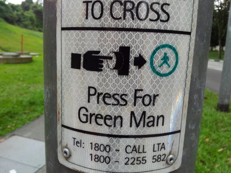 a green man sign on a street post in the grass