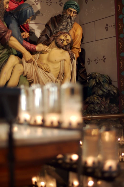 a statue of jesus lying on top of a bed of candles