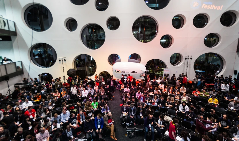 people standing in a large room that has several round windows