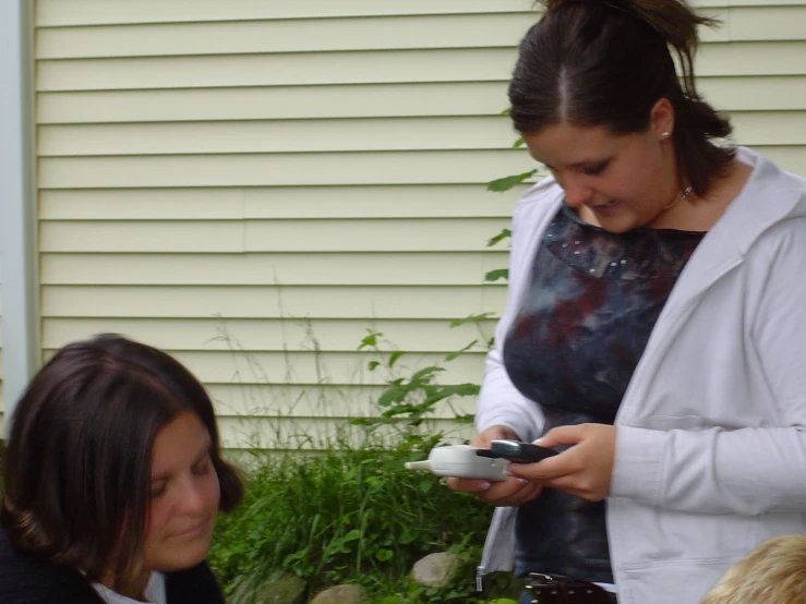 there is a woman holding an electronic device and another woman holding a cell phone