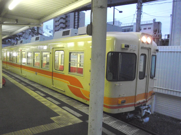 there is an orange and white train at the station