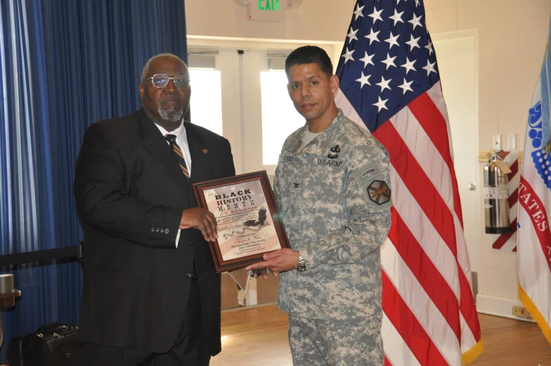 there is an older man presenting a plaque to military members