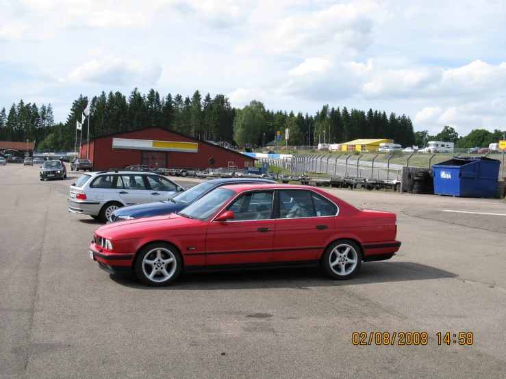 a red car in a parking lot with other cars