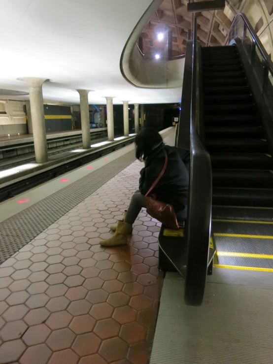 the person with a backpack is sitting near the stair