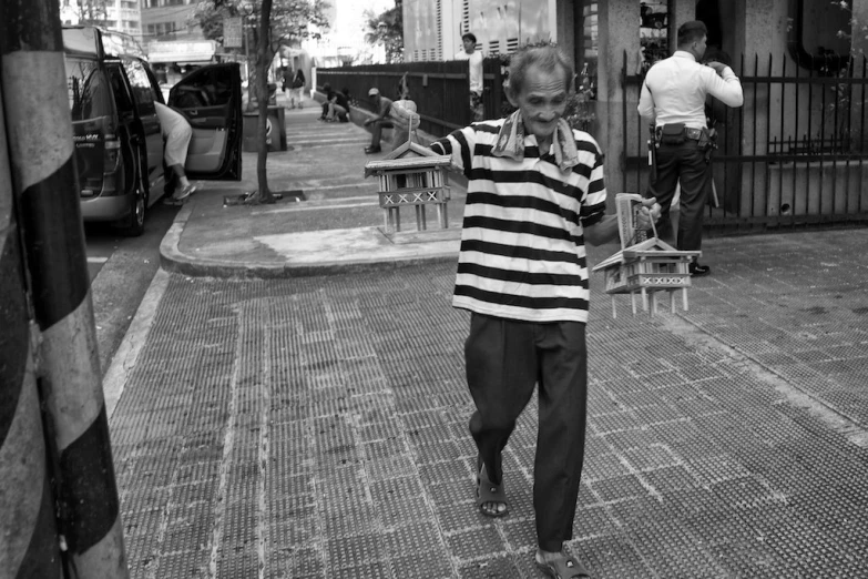 a man walking on the sidewalk wearing a striped shirt