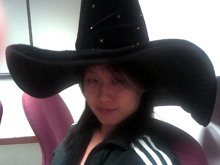 a young woman wearing a black witch hat