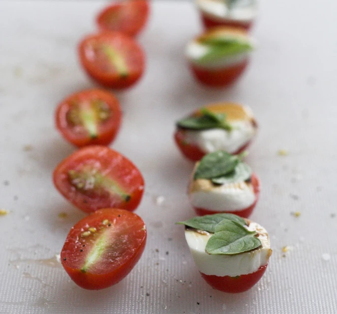 mini mozzarellas with tomatoes and basil leaves are arranged in a row