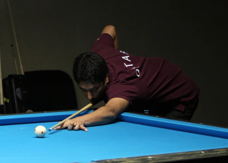 a man laying on the ground with a pool cue near the pool ball