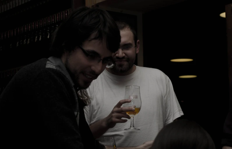 two men are drinking from a wine glass