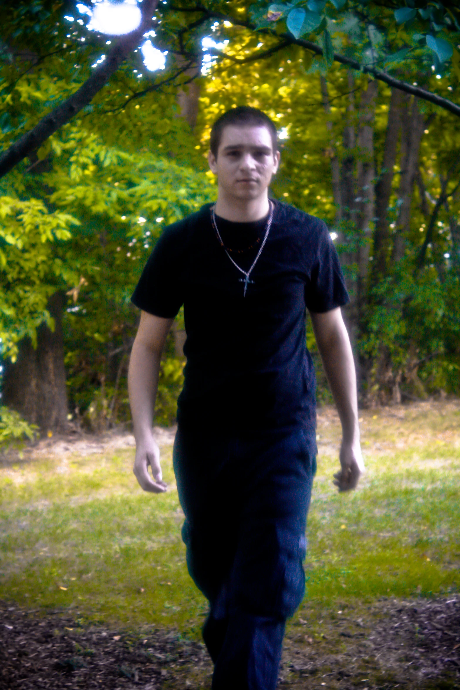 a man walking through the grass with trees in the background