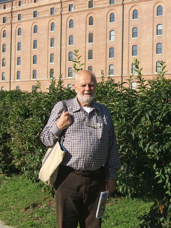 an elderly man stands in front of a stone building