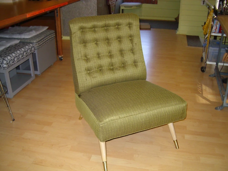 a green chair with wooden legs in a room