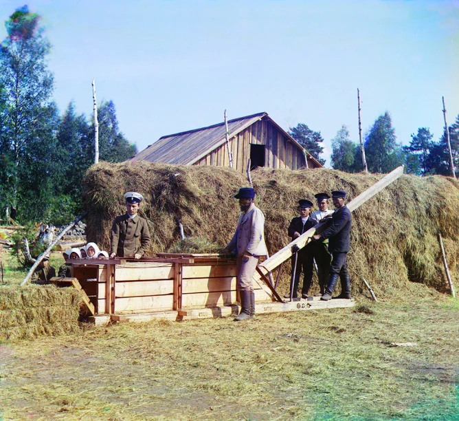 men are gathering around a large pile of hay