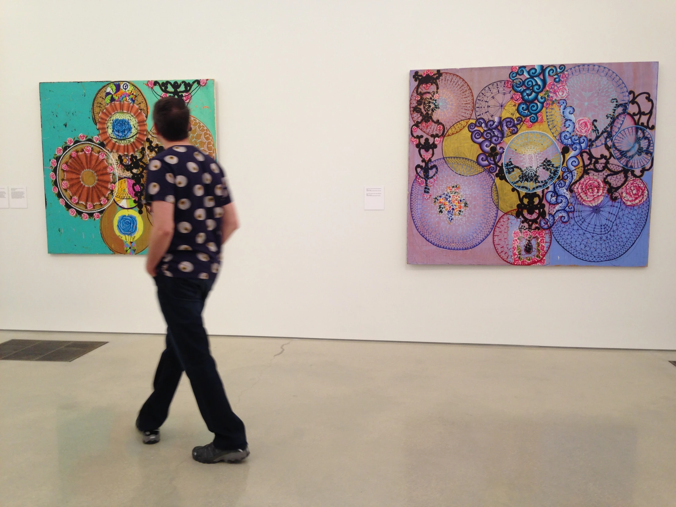 a man is walking in front of two colorful paintings