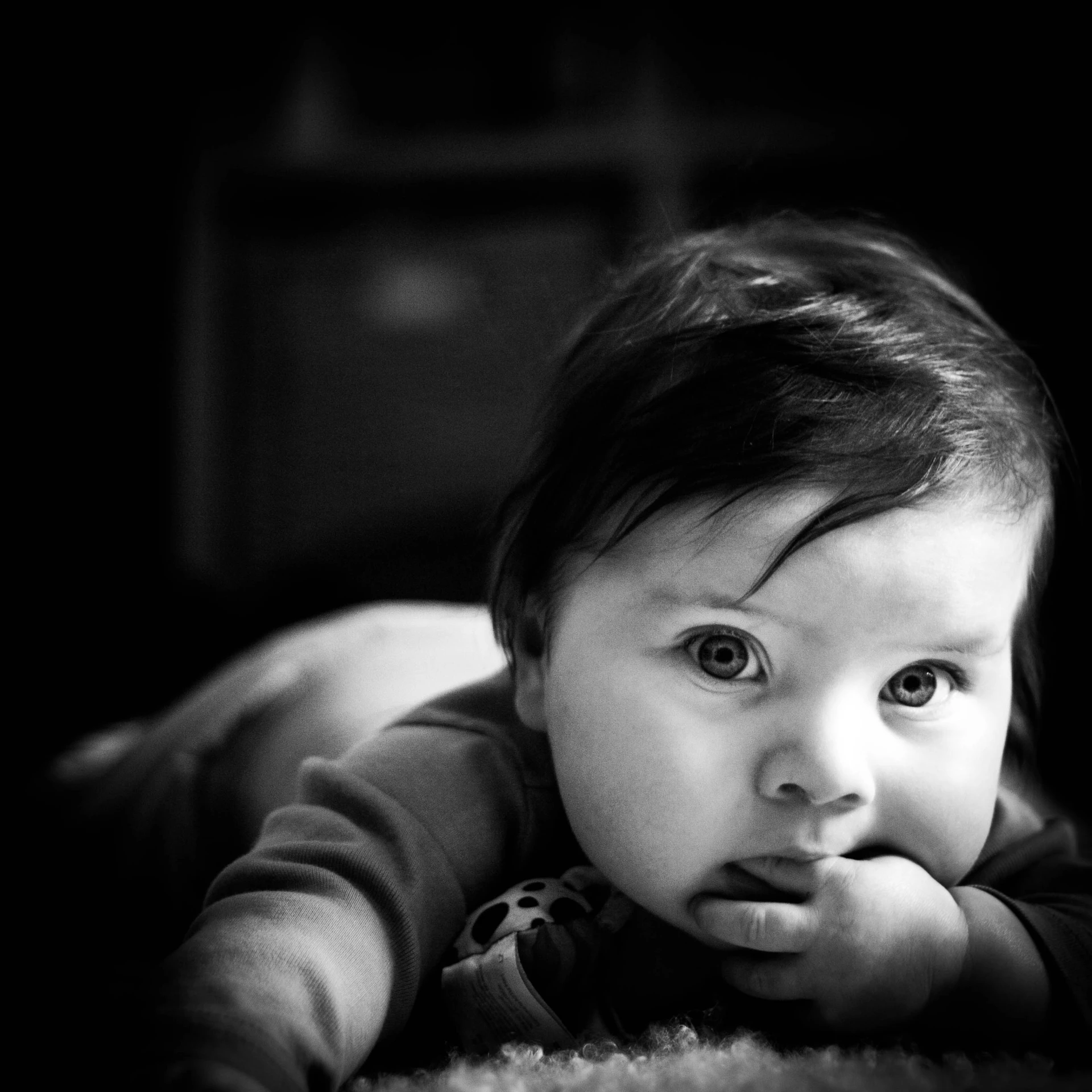 an infant lying on its stomach with his hands under his chin