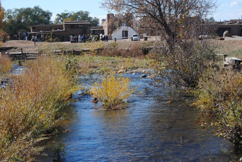 a stream running through a green field with a few people