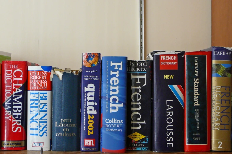 a row of books sitting on top of a wooden shelf