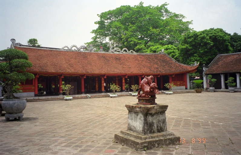 a courtyard in a chinese building with statues and potted trees