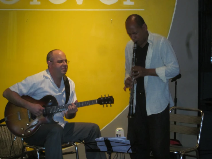 two men playing instruments in front of a poster