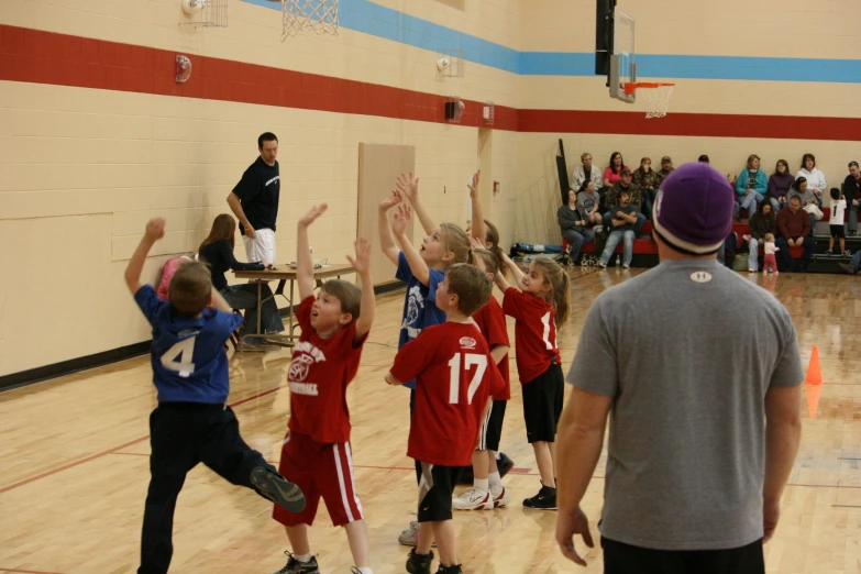 some young children are playing basketball in a gym