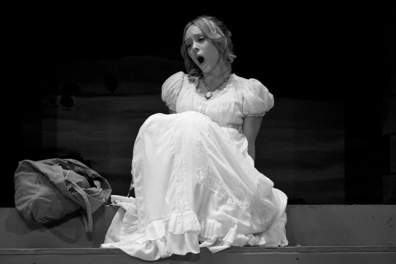 a woman sitting on a ledge in a white dress