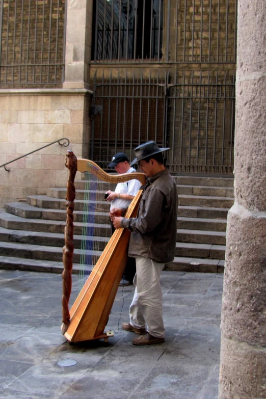 two men are playing harp on the street