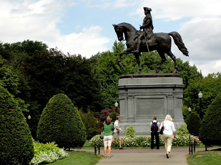 a statue is seen on a walkway in the middle of some park