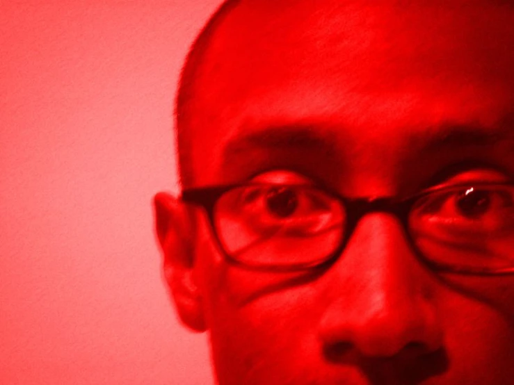 a man with glasses and a red background
