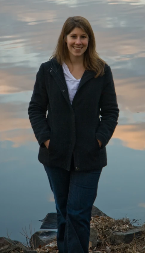 a woman standing on a beach next to a lake