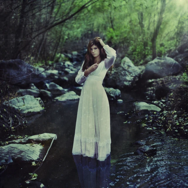 a woman in a white dress standing by some water