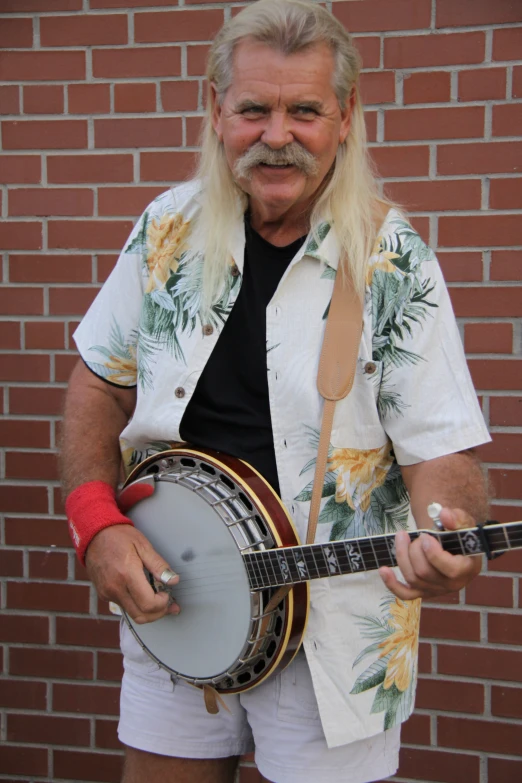 a man in shorts playing the banjo while wearing a hawaiian print shirt