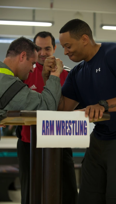 three men working on soing with arm wrestling