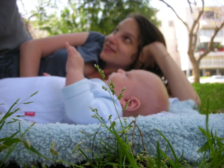 a mother laying on the ground next to a baby