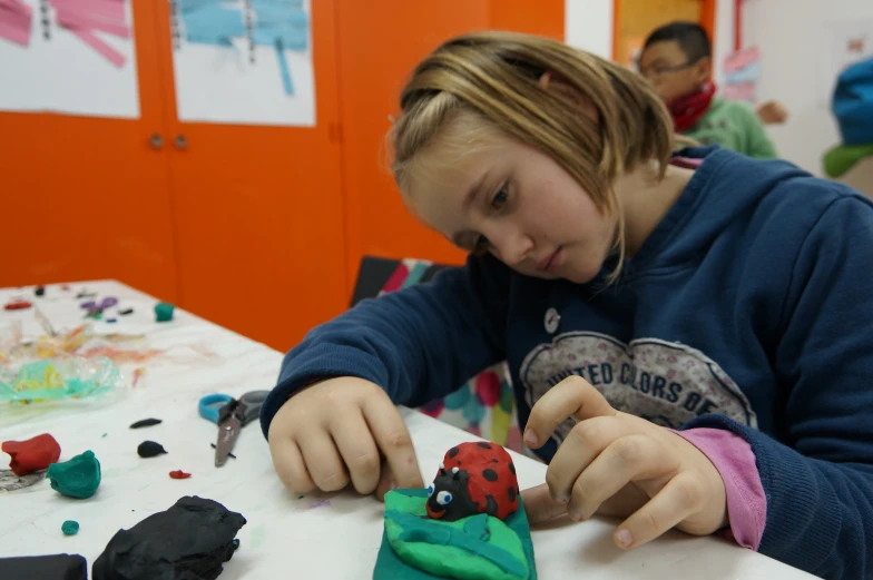 a girl sitting at a table with scissors and making a design