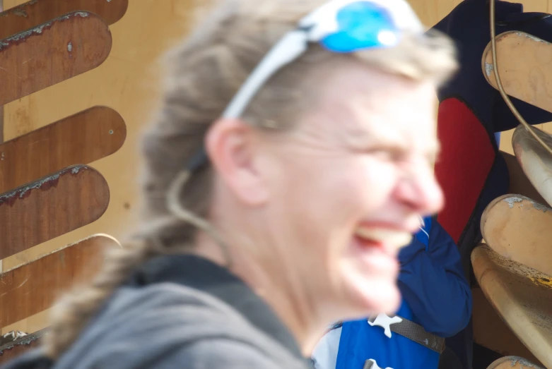 a woman laughs in front of wood canoes