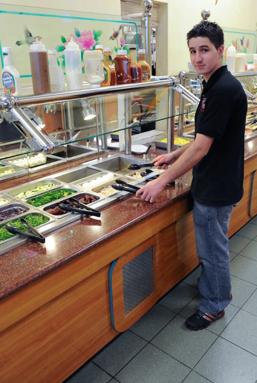 a man in black shirt at counter with food