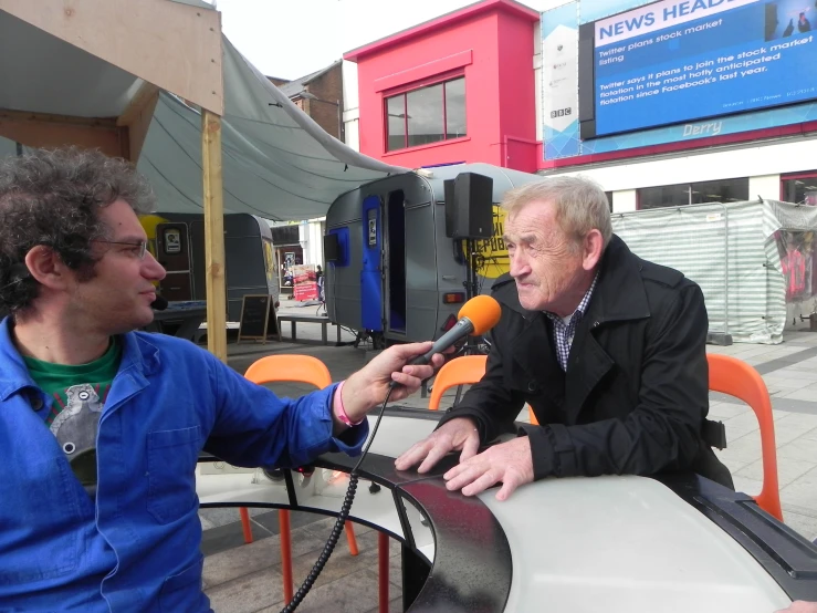 a man talking to an interviewer at a street corner