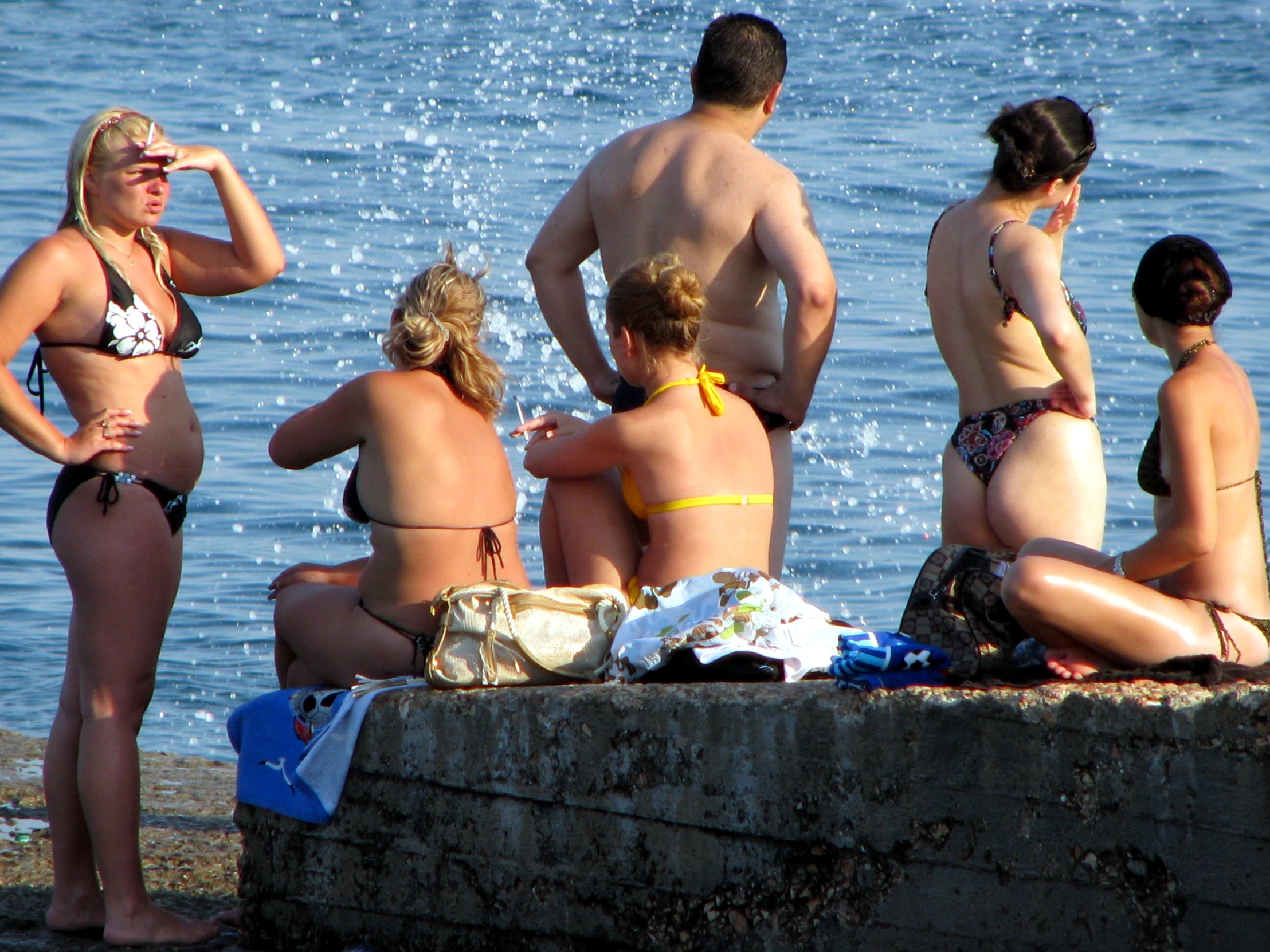 several people sit around on a pier as one looks on