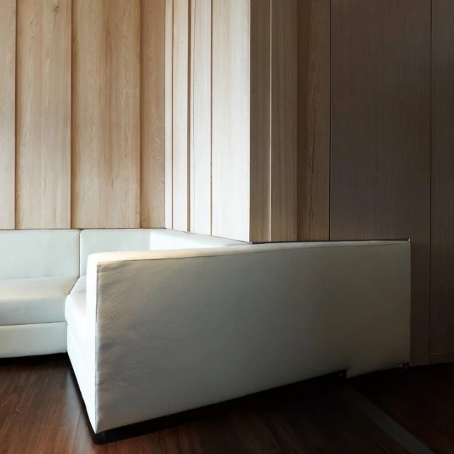 a white couch and chair with wood paneling in an empty room