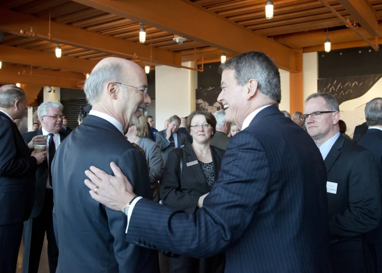 two men in suits standing next to each other in a crowd