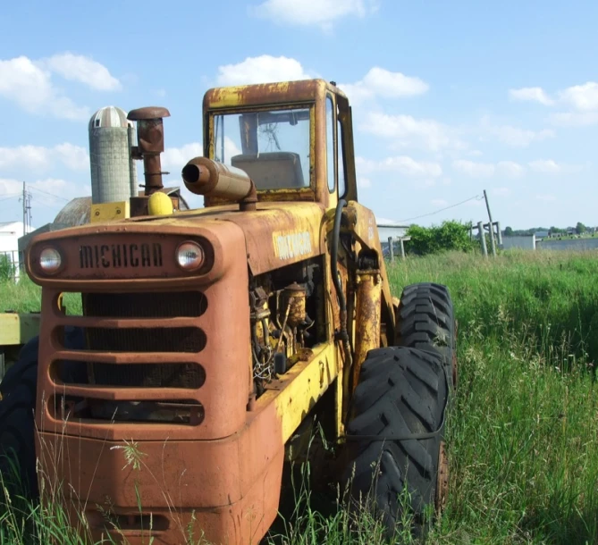 an old yellow truck sitting in tall grass